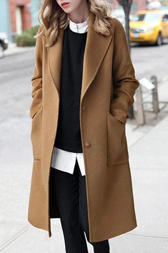 Camel coat με λευκό πουκάμισο, φορεμένο μαύρο πουλόβερ από πάνω και μαύρο jean παντελόνι 